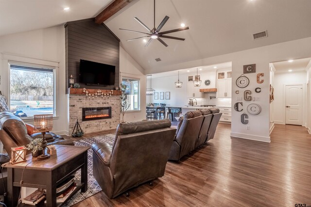 living area featuring a fireplace, visible vents, dark wood finished floors, and beamed ceiling