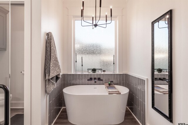 full bathroom with a freestanding tub, wainscoting, and tile walls