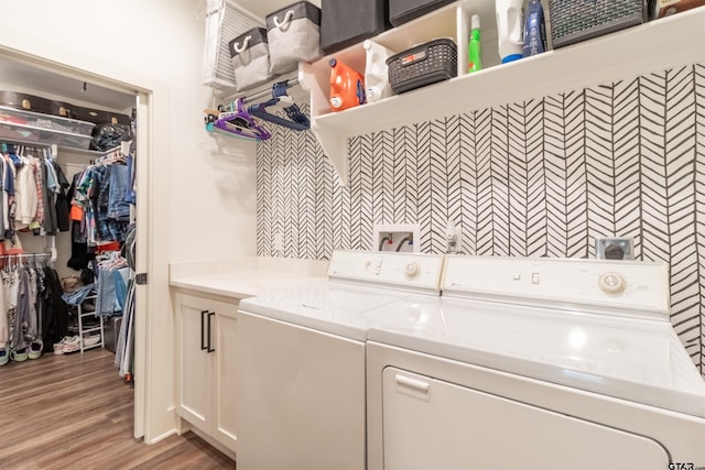 laundry area with cabinet space, light wood finished floors, and separate washer and dryer