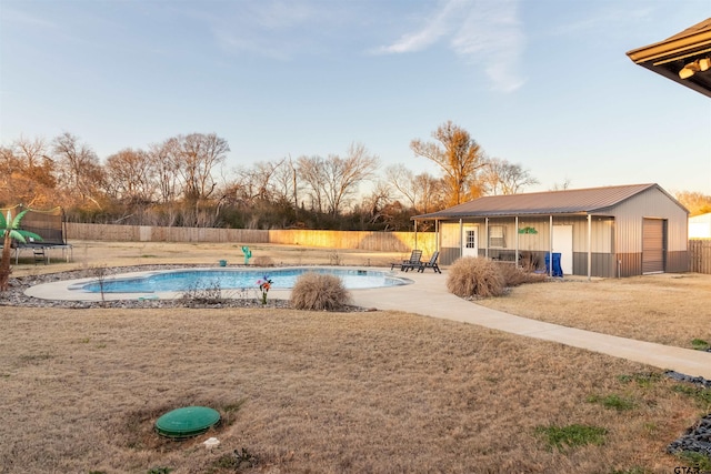 view of swimming pool featuring an outbuilding, a patio, fence, a yard, and a fenced in pool