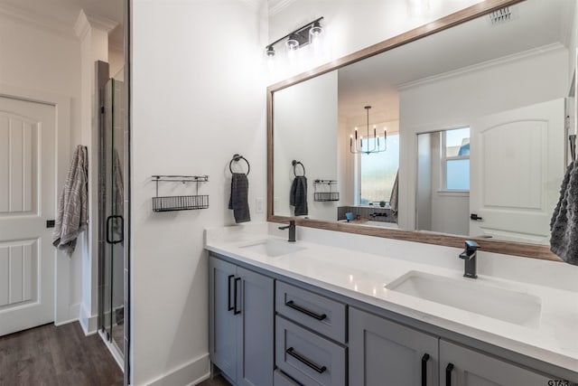 bathroom with crown molding, hardwood / wood-style flooring, vanity, a notable chandelier, and a shower with shower door