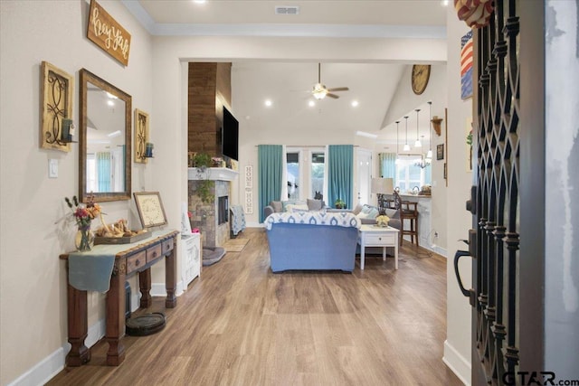 living room featuring a large fireplace, beamed ceiling, hardwood / wood-style flooring, and ceiling fan