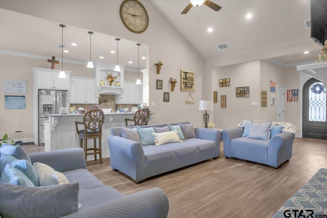 living room with ceiling fan, light hardwood / wood-style flooring, high vaulted ceiling, and ornamental molding