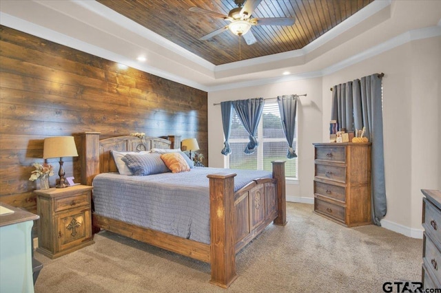 carpeted bedroom with wood walls, ornamental molding, ceiling fan, wood ceiling, and a raised ceiling