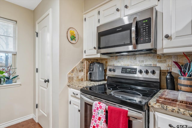 kitchen featuring light stone counters, backsplash, white cabinets, and appliances with stainless steel finishes