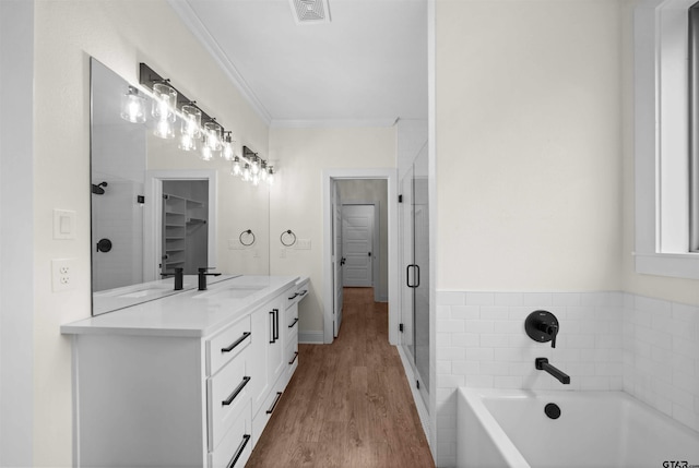 21488 Forest Pl, Flint, TX 75762 - bathroom featuring double vanity, a garden tub, wood finished floors, crown molding, and a stall shower