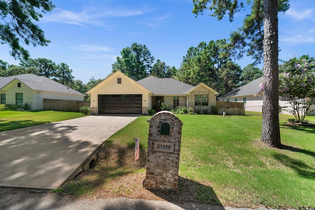 view of front facade with an attached garage, fence, concrete driveway, stone siding, and a front yard