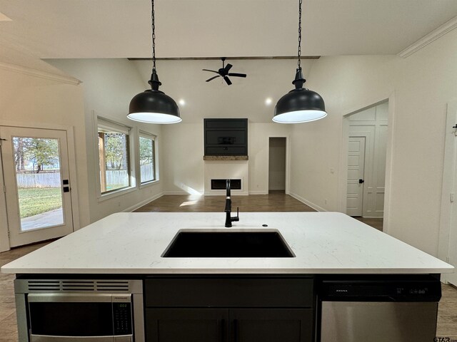 kitchen featuring light stone counters, a sink, open floor plan, appliances with stainless steel finishes, and pendant lighting