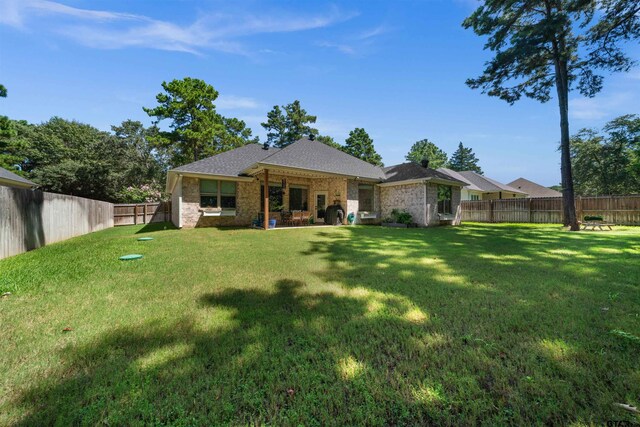 back of house with a fenced backyard and a lawn