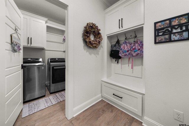 mudroom with light wood-type flooring, baseboards, ornamental molding, and washing machine and clothes dryer