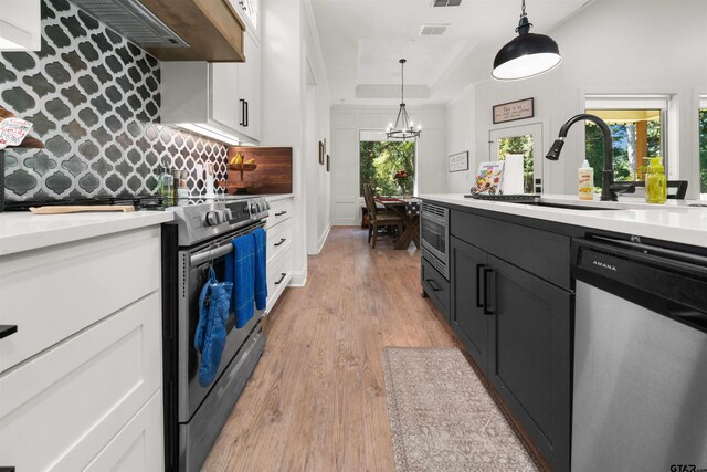 kitchen featuring decorative backsplash, a raised ceiling, stainless steel appliances, light countertops, and white cabinetry