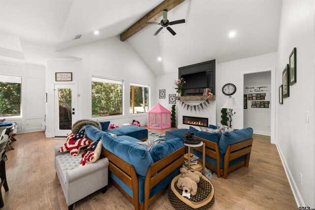 living room with visible vents, a glass covered fireplace, wood finished floors, beamed ceiling, and high vaulted ceiling