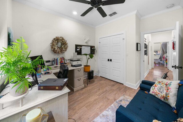 home office featuring light wood finished floors, visible vents, ornamental molding, a ceiling fan, and baseboards