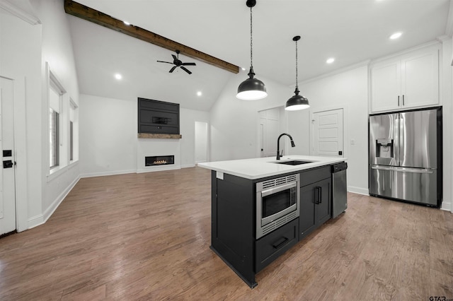 21488 Forest Pl, Flint, TX 75762 - kitchen featuring appliances with stainless steel finishes, light countertops, a ceiling fan, a glass covered fireplace, and hanging light fixtures
