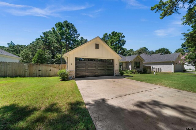 view of front of home with fence, a garage, stone siding, driveway, and a front lawn