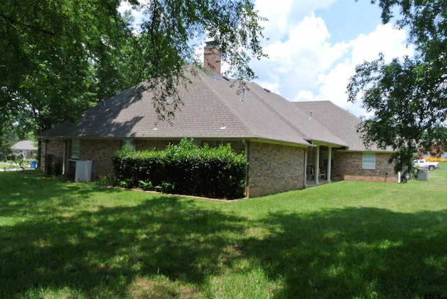 back of house featuring central AC unit and a lawn