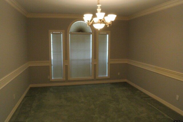 empty room with a chandelier, dark colored carpet, and ornamental molding