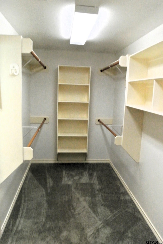 walk in closet with dark colored carpet