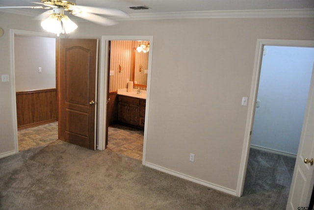 bedroom featuring wood walls, ceiling fan, crown molding, and carpet