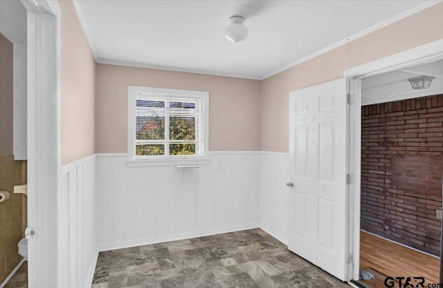 spare room featuring crown molding and brick wall