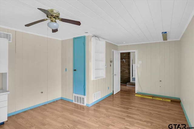 unfurnished bedroom featuring ceiling fan, wooden walls, light wood-type flooring, and crown molding