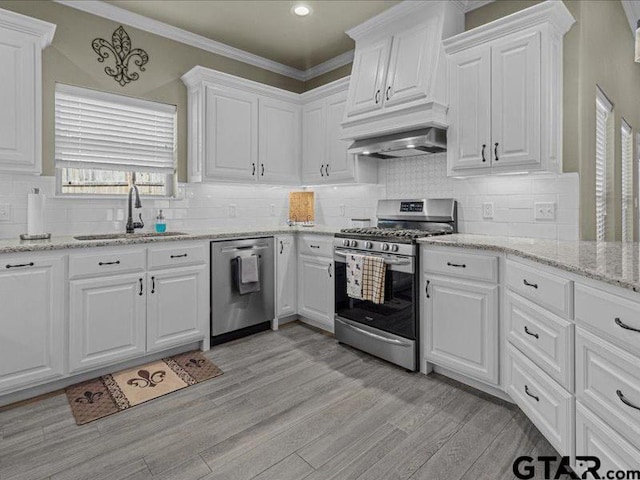 kitchen featuring white cabinetry, light hardwood / wood-style floors, appliances with stainless steel finishes, wall chimney exhaust hood, and sink