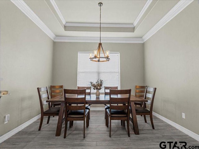 dining space featuring an inviting chandelier, ornamental molding, and a tray ceiling