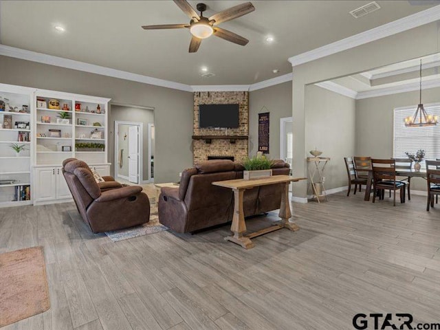 living room with ceiling fan with notable chandelier, ornamental molding, a fireplace, and light hardwood / wood-style flooring