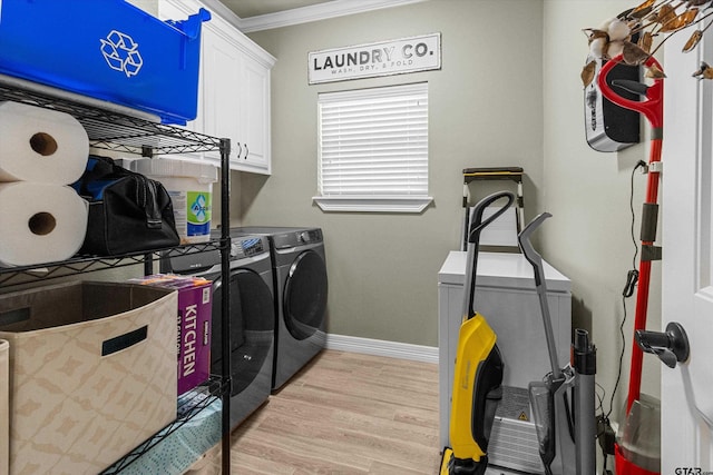 laundry room featuring cabinets, light wood-type flooring, washing machine and clothes dryer, and ornamental molding