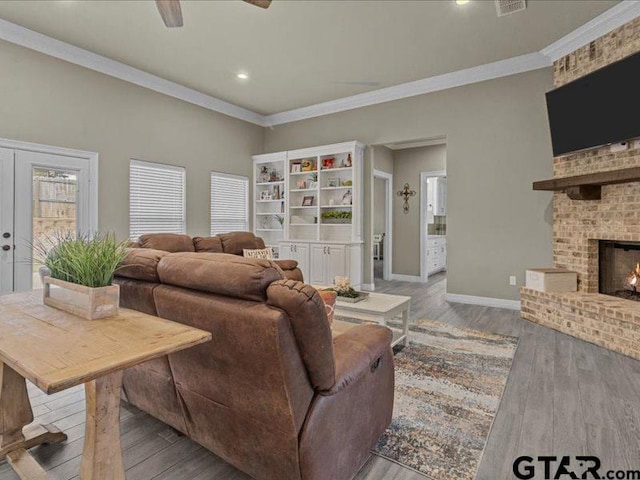 living room with a brick fireplace, light hardwood / wood-style flooring, and crown molding