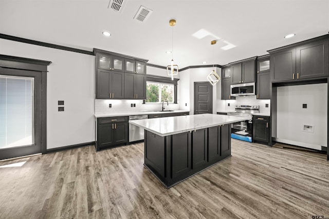 kitchen with stainless steel appliances, light hardwood / wood-style flooring, hanging light fixtures, and ornamental molding