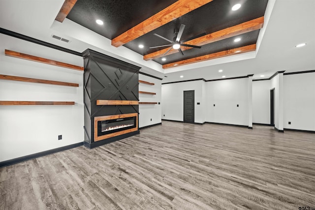 unfurnished living room with ceiling fan, a raised ceiling, hardwood / wood-style flooring, a fireplace, and ornamental molding