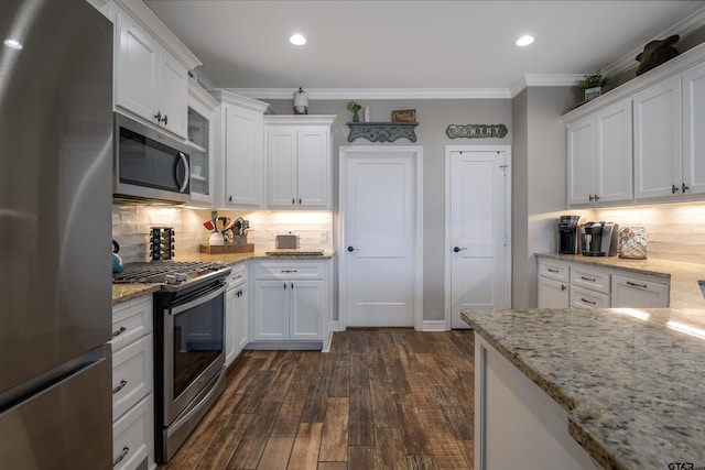 kitchen with dark wood-type flooring, white cabinetry, ornamental molding, appliances with stainless steel finishes, and backsplash