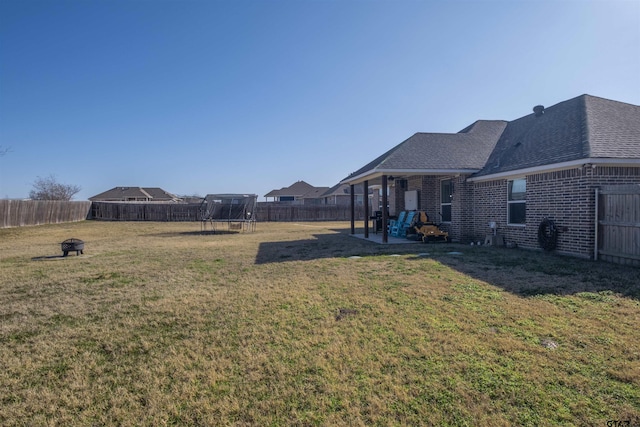 view of yard with a trampoline and a patio area