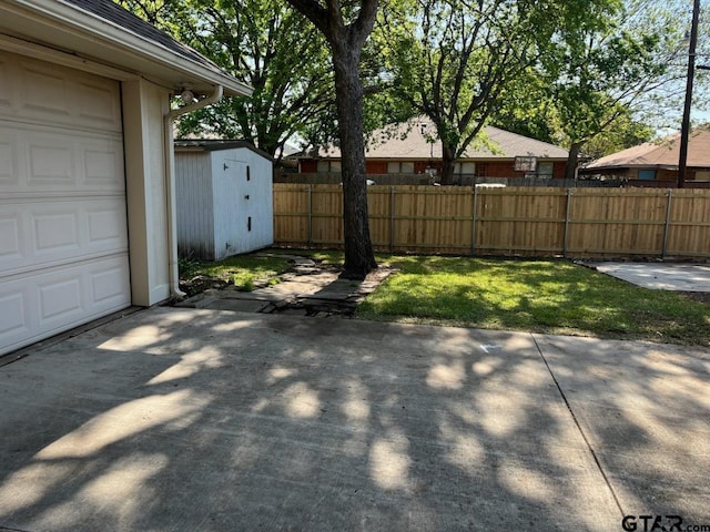 exterior space featuring a storage shed, a garage, an outdoor structure, fence, and a patio