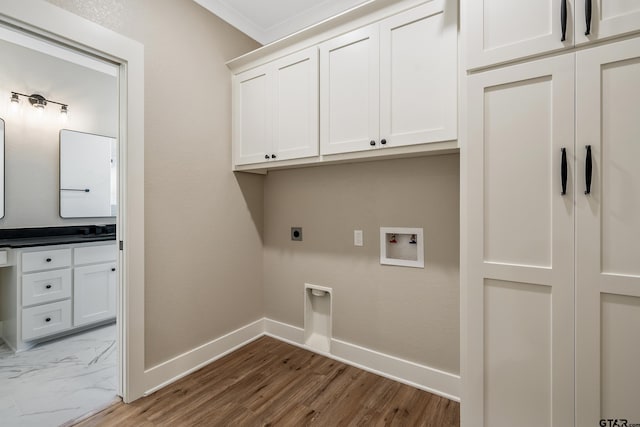 laundry room with crown molding, hookup for an electric dryer, washer hookup, cabinets, and hardwood / wood-style floors