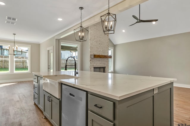 kitchen with stainless steel dishwasher, light hardwood / wood-style floors, a center island with sink, and plenty of natural light