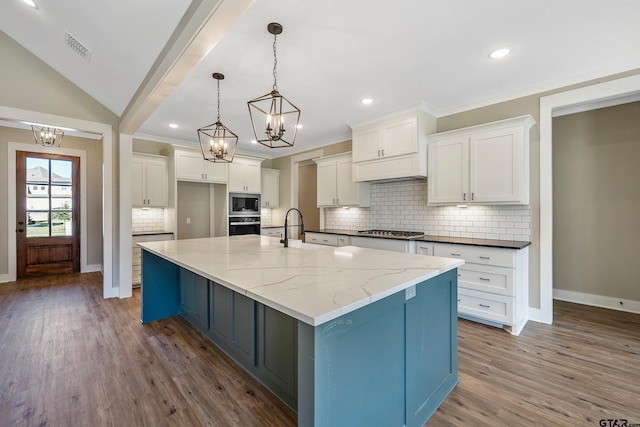 kitchen with white cabinets, light wood-type flooring, a spacious island, and dark stone countertops