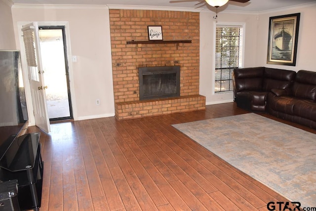 living room with dark hardwood / wood-style floors, a fireplace, crown molding, and ceiling fan