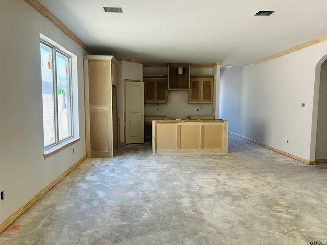 kitchen with baseboards, arched walkways, unfinished concrete flooring, ornamental molding, and a center island