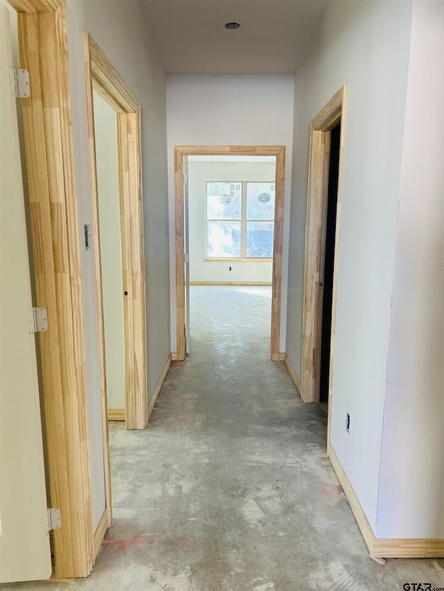 hallway with concrete flooring and baseboards