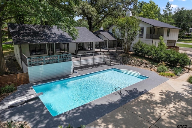 view of pool with a deck, a diving board, and a patio area