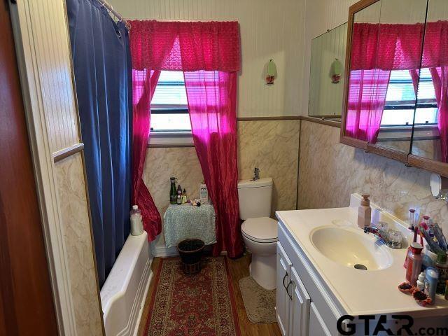 full bathroom with hardwood / wood-style flooring, vanity, toilet, and shower / bath combo