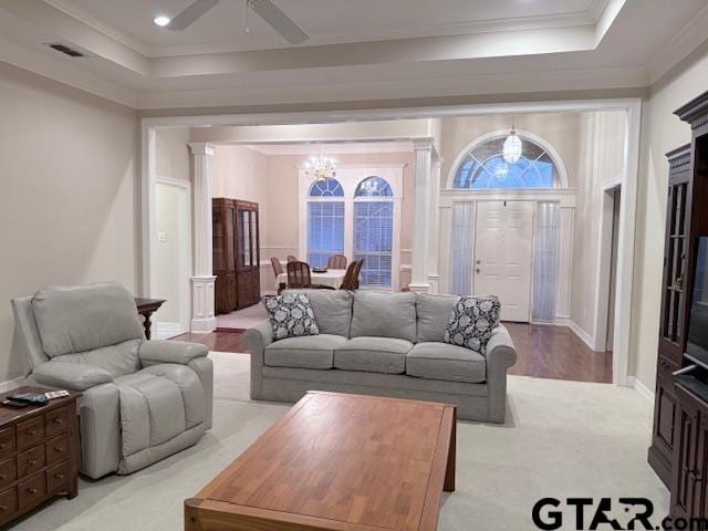 living room featuring a tray ceiling, crown molding, and ceiling fan with notable chandelier