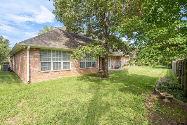 rear view of property featuring a lawn and central air condition unit