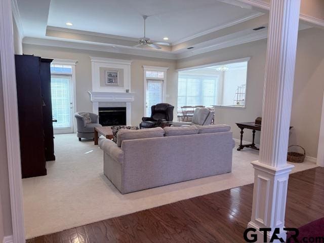 living room with a tray ceiling, ceiling fan, crown molding, and wood-type flooring