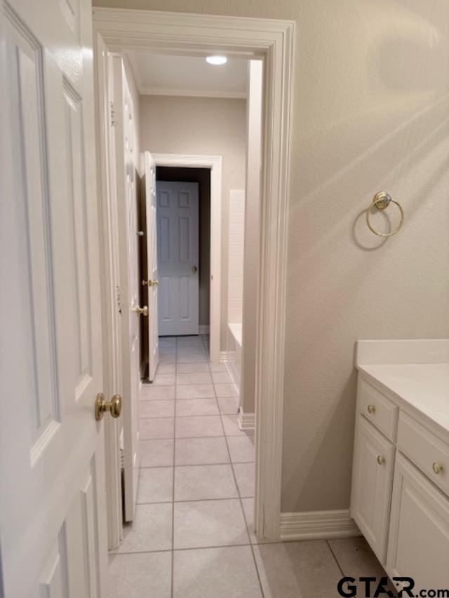 corridor featuring light tile patterned floors and ornamental molding