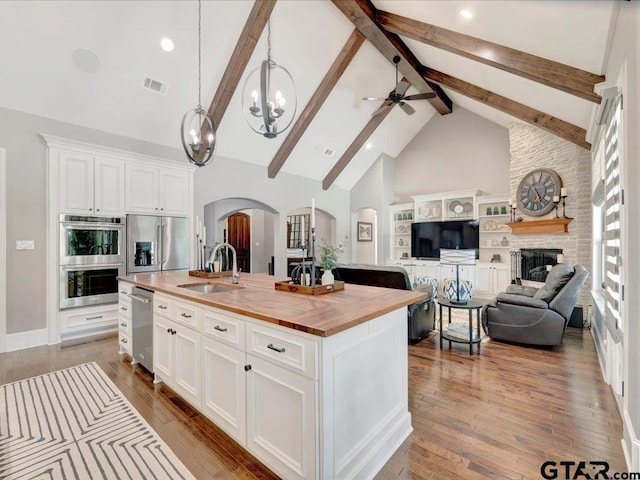 kitchen featuring visible vents, arched walkways, a sink, wood counters, and appliances with stainless steel finishes