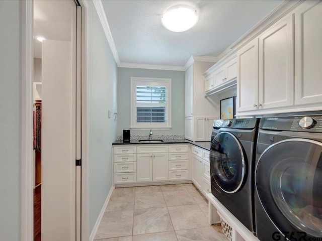 laundry room with crown molding, cabinet space, a sink, baseboards, and washer and clothes dryer