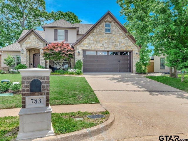 view of front facade featuring an attached garage, a front yard, stone siding, and concrete driveway